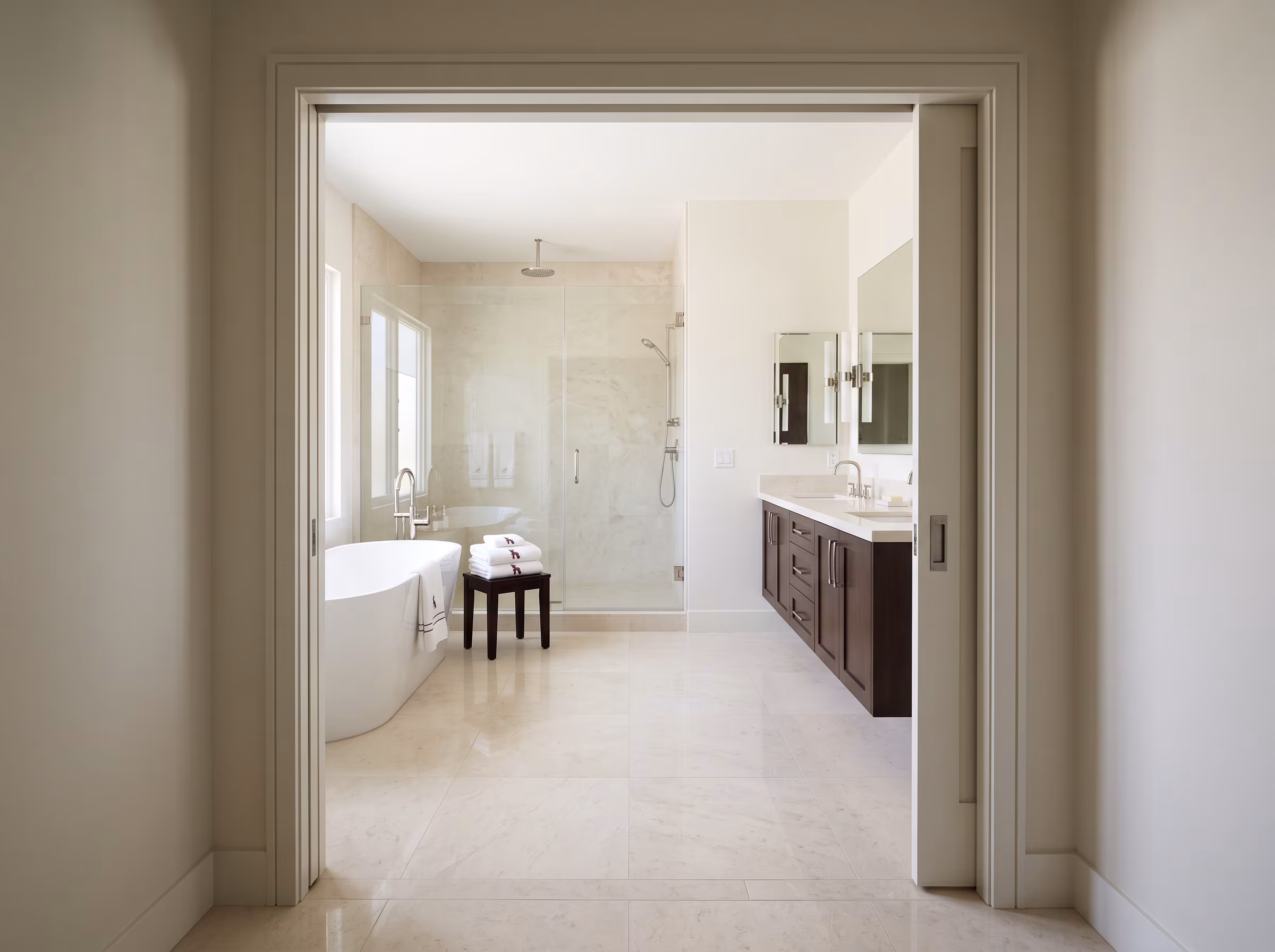 Bathroom doorway and open floor leading into a bright residential bath