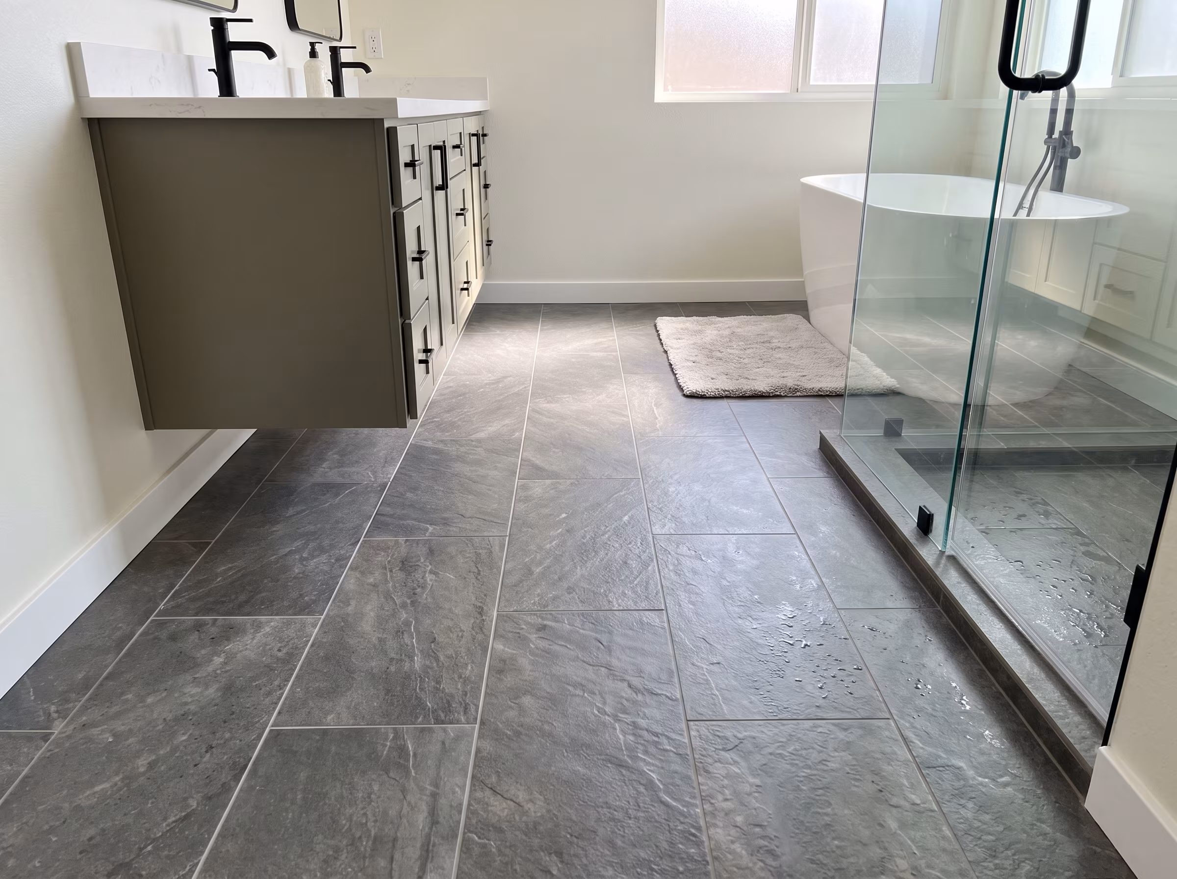Bathroom with large-format charcoal porcelain floor tile and a floating vanity