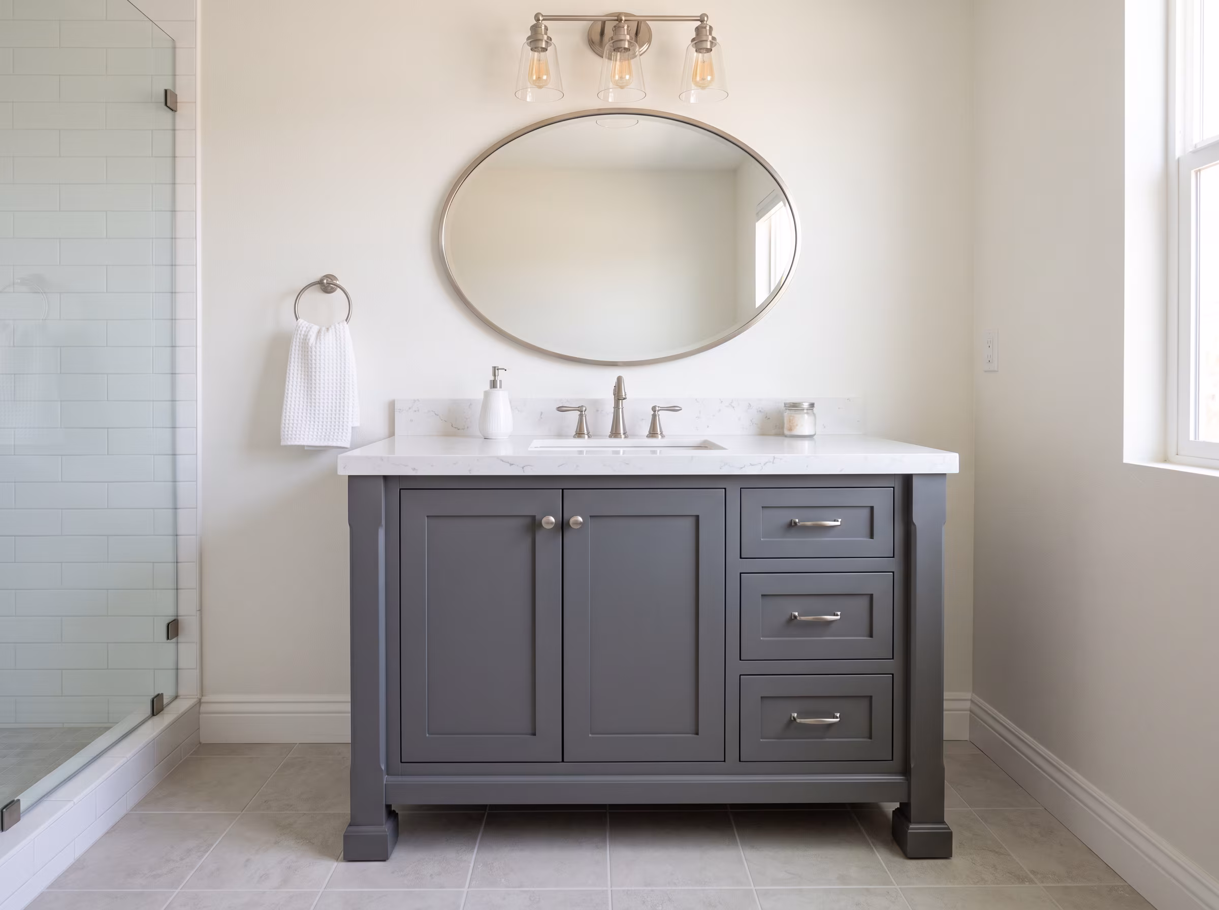 Freestanding gray shaker vanity with drawers, white countertop and oval mirror
