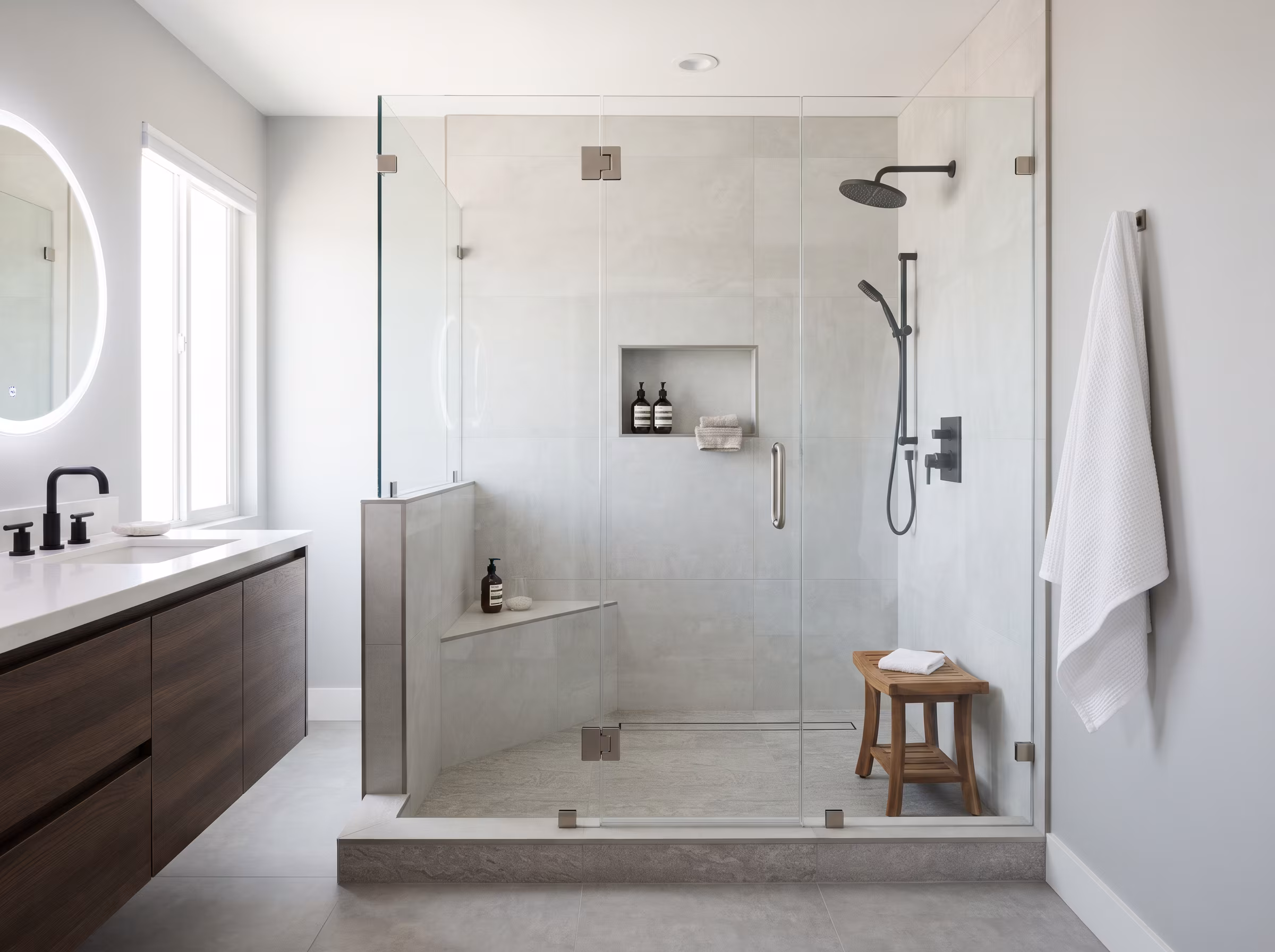 Marble walk-in shower with glass enclosure, tiled bench and niche after a full rebuild
